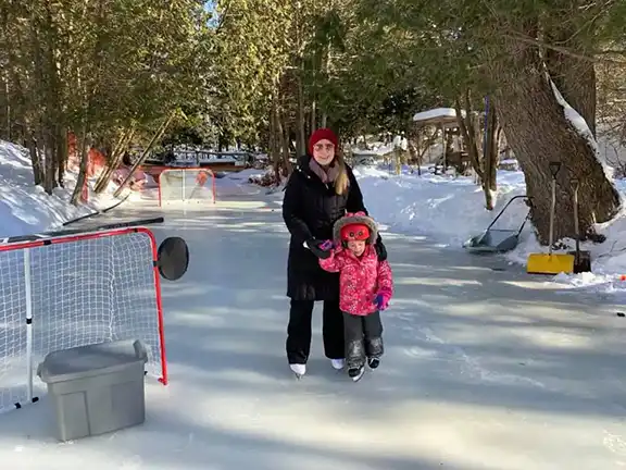 Amber Mcgarvey-Moreland, holding the hand of her daughter while both are skating on a homemade rink