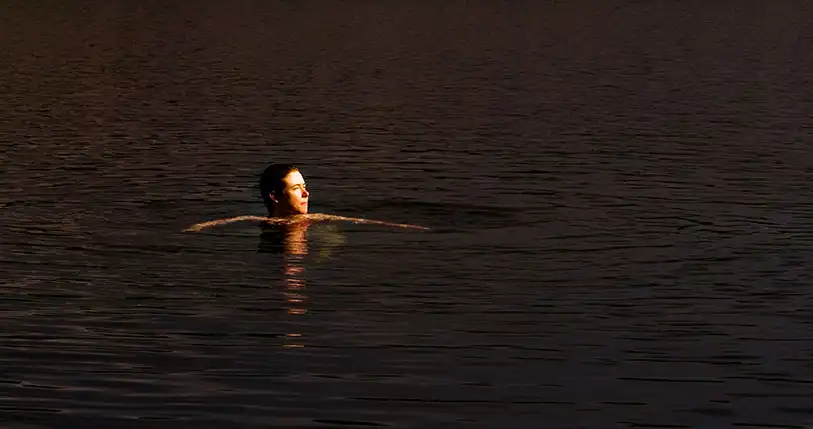 Fiona Innis, swimming in a lake. Only her head and arms can be seen above the water