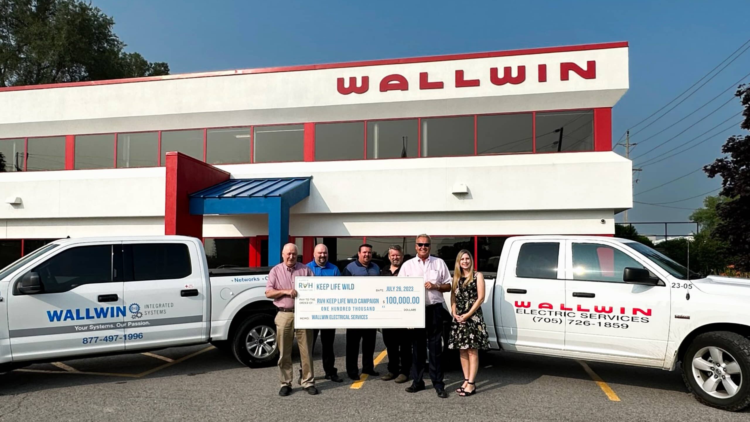 A group poses with a large oversized cheque outside of Wallwin Eletric Services LTD. 
